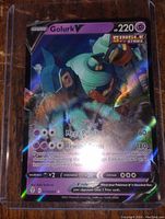 Photo of Golurk V Holo foil full art Pokemon card inside plastic protective holder showing front of card with holographic art and text details.
