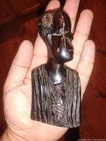 Front view of the hand carved ebony bust showing detailed facial features and textured garment.