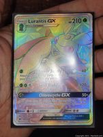 Full view of Lurantis GX full art rainbow holo foil card held in hand, showing vibrant colors and text details.