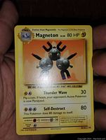 Photo of front side of Magneton Pokemon card held in hand showing card details and image