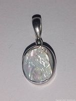 Front view of the oval pendant showing hand-carved horse head cameo in iridescent mother of pearl set in sterling silver bail.