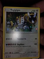 Image showing the holographic Regigigas Pokémon card held by a hand, focusing on the card front including artwork, stats, and attacks.