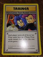 Photo of a Pokemon Trainer card titled 'Here Comes Team Rocket!' showing artwork of Team Rocket characters and card text.