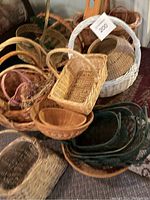 Photo showing a variety of wicker baskets in natural and white finishes, different sizes including a rectangular wicker basket and a white painted one with a tag attached.