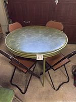 Full view of round folding card table with four matching folding chairs around it in a garage setting.
