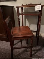 Small wooden children's chair placed beside the wooden desk. Chair has turned legs and a simple square seat.
