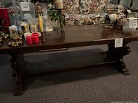 Full view of the rectangular solid wood coffee table with dark finish showing the tabletop, base, and lower shelf. Minor scratches visible.
