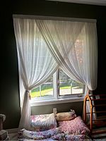 Pair of white sheer curtains hung and tied back on a window in a room with green walls. The curtains are sheer and lightweight, fitting a 56-inch window.
