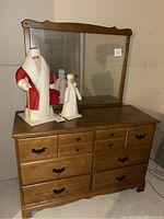 Full front view of wooden dresser with attached large mirror and two decorative figurines on top.