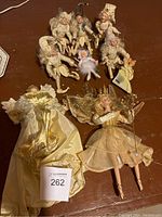 Photo showing angel tree topper, fairy figurine, and nine small elf or fairy figures arranged on table