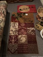 View of all three mats: the red Santa sleigh outdoor mat, the 'Season's Greetings' coir outdoor mat, and the indoor decorative rug with patchwork design.