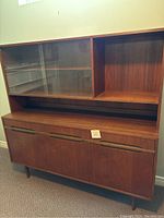 Front view of two-piece cabinet showing hutch with glass sliding doors and open shelves above base