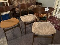 Three mid-century modern wooden chairs with curved backrests, two with beige damask patterned fabric seats, one with worn orange fabric needing reupholstery.