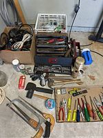 Full view of the hand tools on the floor including boxes of wires, hand tools, and miscellaneous hardware.
