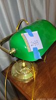 Front angle of green glass shade with brass base showing lamp details and attached electrical cord