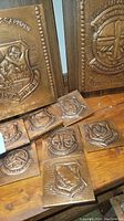 Nine copper-covered military award plaques displayed on a wooden surface including large and smaller sizes with detailed embossed military symbols