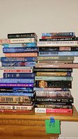 Stack of about 30 non-fiction books on various topics including literature, history, and true crime, visible titles and spines shown to identify books.