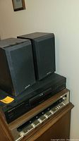 Two Pioneer bookshelf speakers positioned on top of Pioneer stereo amplifier and CD player/tuner units.