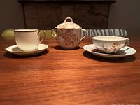 Set of three demitasse teacups on saucers displayed on a wooden table with a stone fireplace background.