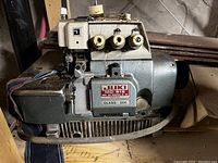 Close-up of Juki MO-816 serger sewing machine showing control dials, manufacturer label, and metal body.