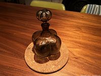 Side view of the smoked glass decanter sitting on a cork base, showing its rounded, lobed shape and stopper.