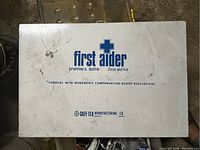 Closed metal first aid kit box with blue branding and text.