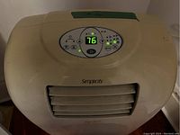 Top front view of beige Simplicity portable air conditioner showing digital control panel with LED screen displaying temperature, mode and power buttons illuminated.