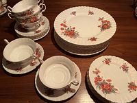 Stack of 8 dinner plates, 8 side/bread plates, and grouped cups and saucers showing rose floral pattern and gold trim