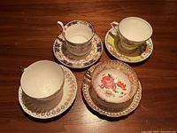 Top view of all four teacups with saucers, showing varied floral and gold designs.