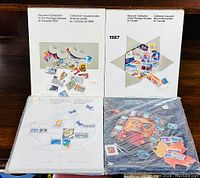 Four Canada postage stamp albums from 1986, 1987, 1988, and 1989 displayed on a wooden surface, each sealed in shrink wrap.