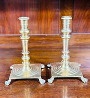 Pair of solid brass antique candlesticks on wooden surface with polished finish.