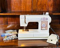 Janome Model 344 Limited Edition sewing machine on wooden surface with foot pedal and two bags of sewing accessories.