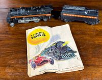 Locomotive and tender positioned on wooden surface next to folded Lionel 1963 catalog featuring a train and race car on the cover.