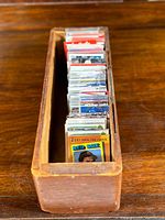 Wooden tray filled with a collection of various sports trading cards upright, showing a mix of vintage and contemporary cards.