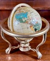 Front perspective showing the gemstone inset globe and metal base stand.
