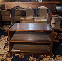 Front view of 4 tier solid wood shelf showing carved scalloped apron detail on top and all four shelves