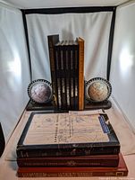 Front view of the books arranged between two globe bookends showing book spines and part of globe details.