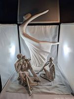 Full view of three decorative statues including the largest woman dancing figure and two smaller seated couples.
