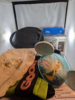 Photo showing the signed black Goofy hat, large Tinker Bell Mickey ears hat, and beige crochet floral hat with Tinker Bell applique; background includes boxed Disney collectible items.