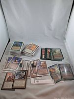 Photo of multiple stacks of Magic The Gathering cards from the early 1990s laid out with some cards overlapping showing details of the card face including creatures, spells, and artifacts.