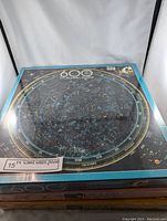 Top view of five F.X. Schmid sealed puzzle boxes stacked, showing the celestial star chart puzzle on top.