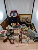 Photo showing multiple items including framed print, stained glass panel, perfume, incense, necklaces, ashtrays, and decorative pieces.