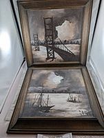 Two framed paintings stacked with visible subject matter - bridge and boats on water