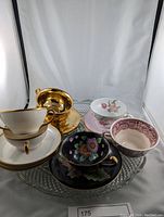 Full lot of assorted teacups and saucers on a glass tray, showing various brands and styles