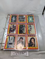 A binder page showing 12 collectible cards with yellow and red borders from 1979 Alien and 1988 Dinosaur Attacks sets.
