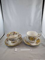 Two vintage fine china teacups and saucers side by side, showing floral patterns and gold trim details.