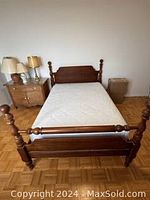Front view of the cherry wood bed frame with mattress on it to show structure, headboard, footboard, side rails, and wooden slats underneath mattress.