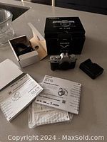 Group shot showing camera body, original boxes, charger and manuals