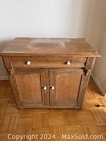 Front view of antique solid wood chest showing one drawer and two doors with white knobs, curved front drawer and carved detailing.