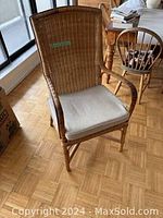 Wicker chair with cushion in room setting, showing full chair and cushion.